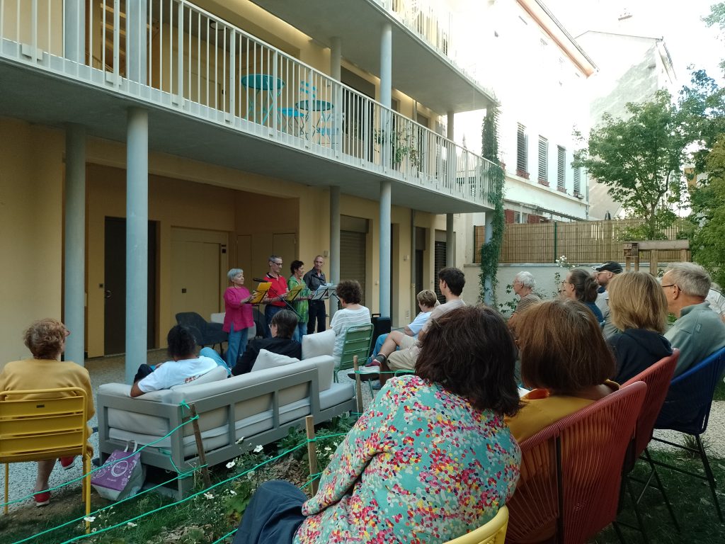 Jardin de la Maison de la diversité, lecture théâtrale : public installé sur des chaises faisant face à une ligne de 4 lecteurices 