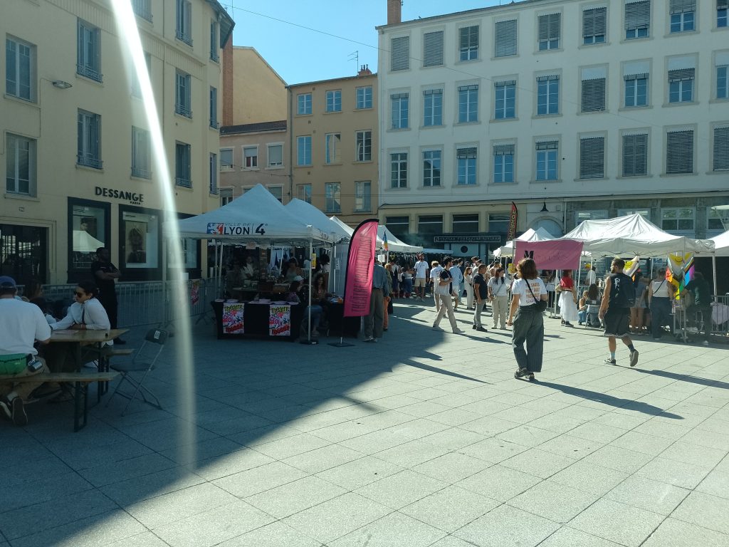 Place du théâtre, entrée du festival : stands associatifs sous des barnums blanc 