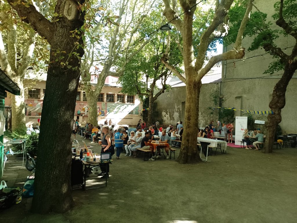 Clos bouliste à l'arrière du théâtre : personnes installées aux tables sous les arbres